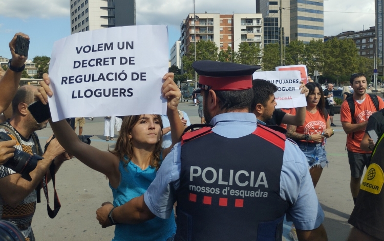 A tenants' union activist holding a sign in front of a Mossos d'Esquadra police agent in Barcelona on September 16, 2022 (courtesy of the tenants' unions)